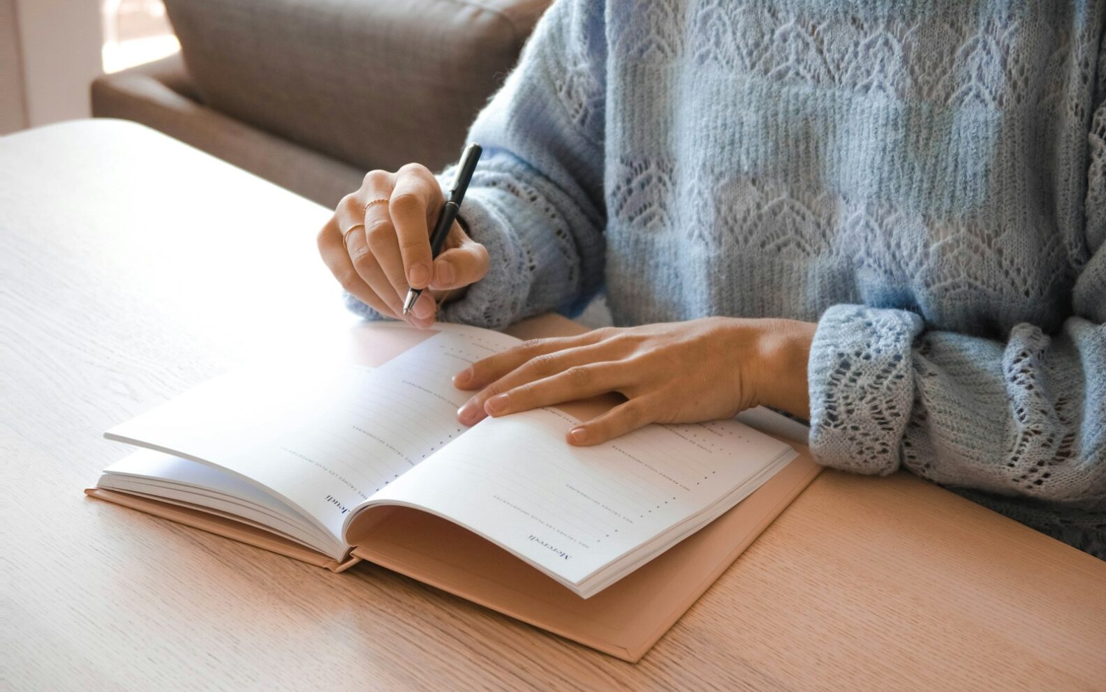 woman in white and gray sweater writing on white paper
